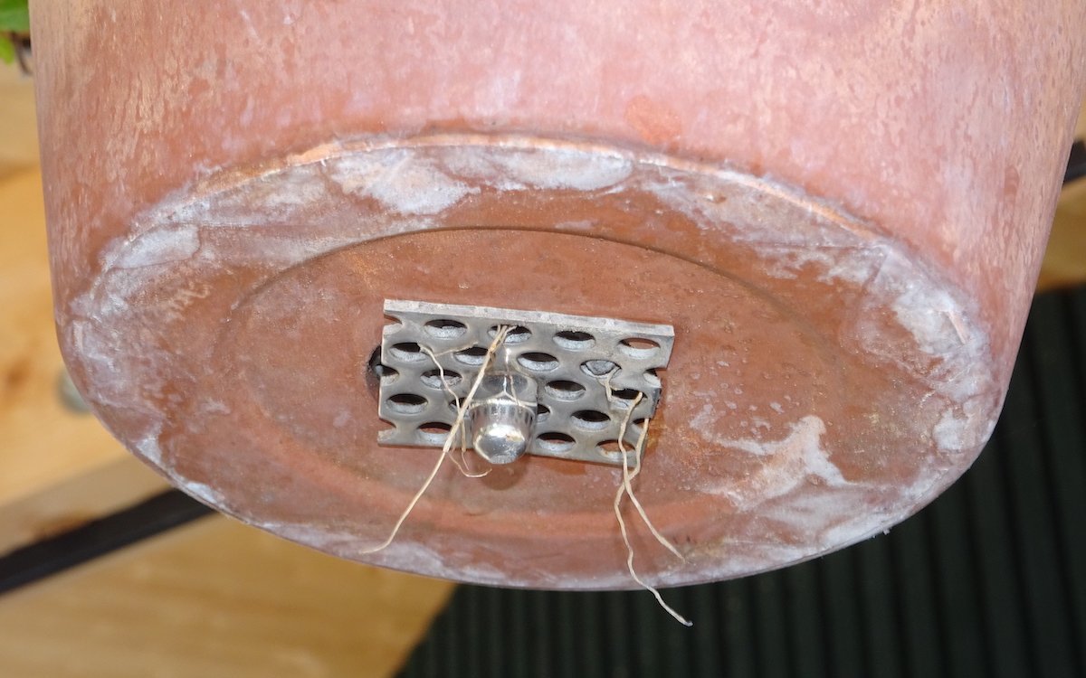 Das Lochblech unterhalb des Lochs im Tontopf fixiert die sich durch den Topf ziehende Kette. 